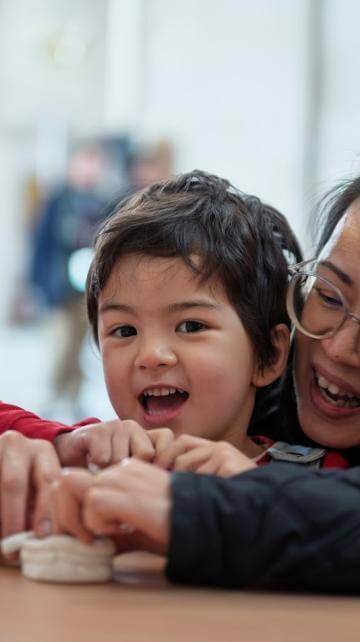 Primary school ages boy and mother making sculpture from white clay.