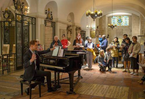 Man at piano directing parents and children