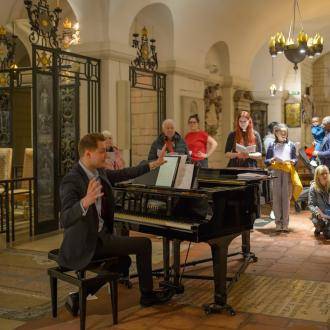 Man at piano directing parents and children
