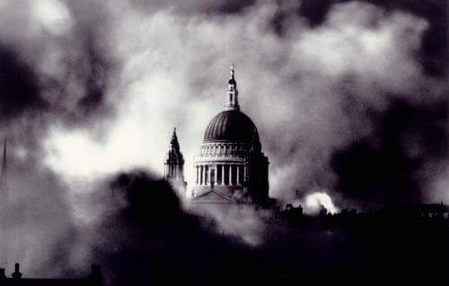 a black and white image of St Paul's Cathedral dome visible above a cloud of smoke at night