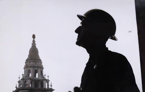 a silhouette of a male figure wearing a hat against a background of St Paul's bell tower